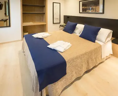a large bed with blue sheets and white towels on it at Hotel Roma in Sarria