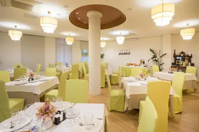 a restaurant with white tables and yellow chairs at Hotel Roma in Sarria