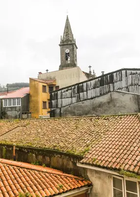 a clock tower on top of a building with a roof at A Casa do Latoneiro in Caldas de Reis
