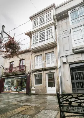 a building on a street with a bench in front of it at A Casa do Latoneiro in Caldas de Reis
