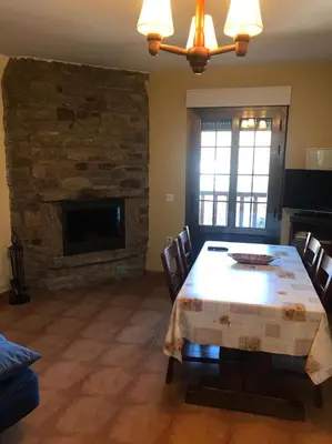 a dining room with a table and a stone fireplace at El Pajar in San Ciprián
