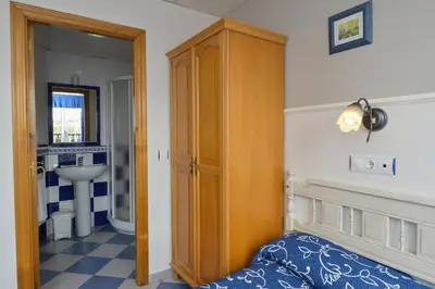 a bedroom with a bed and a wooden cabinet at Hostal Linares in Ribadeo