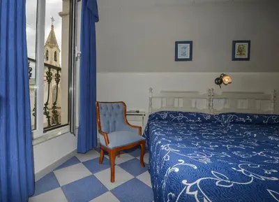 a bedroom with a bed and a chair and a window at Hostal Linares in Ribadeo