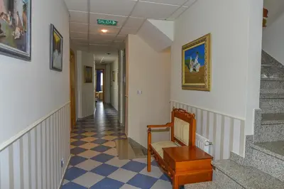 a hallway with stairs and a chair in a building at Hostal Linares in Ribadeo