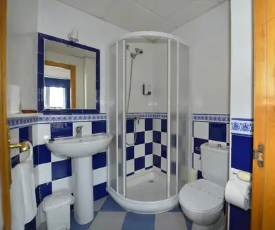 a bathroom with a sink and a shower and a toilet at Hostal Linares in Ribadeo