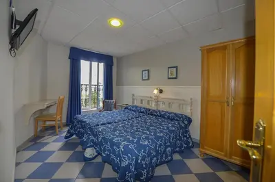 a bedroom with a bed and a table and a window at Hostal Linares in Ribadeo