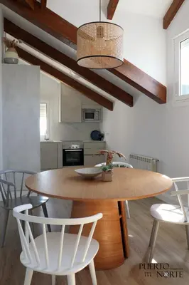 a kitchen with a wooden table and white chairs at Apartamentos Puerto Norte - Apto 1 in Puerto de Vega