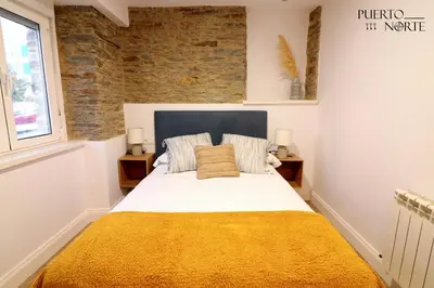 a bedroom with a large bed with a yellow blanket at Apartamentos Puerto Norte - Apto 1 in Puerto de Vega