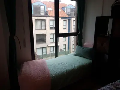a bedroom with a window looking out at a building at Pintoresco piso a 5 min de la playa wifi/Netflix in Ares