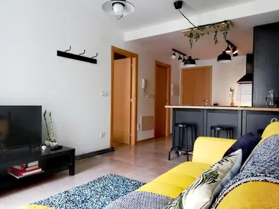 a living room with a yellow couch and a kitchen at Pintoresco piso a 5 min de la playa wifi/Netflix in Ares