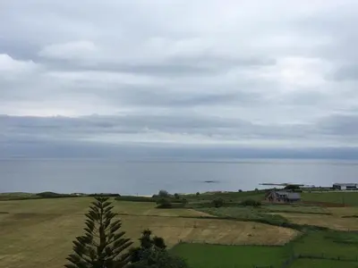 a view of a field with a house and the ocean at Villa De Foz in Foz