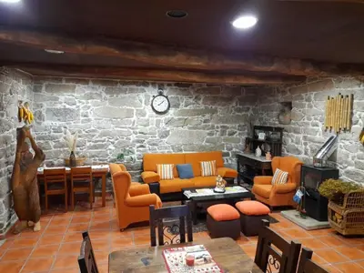 a living room with orange furniture and a stone wall at Albergue Rectoral de Romean in Lugo