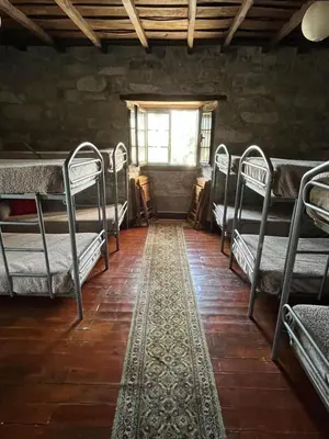 a room with bunk beds and a window and a rug at Albergue Rectoral de Romean in Lugo