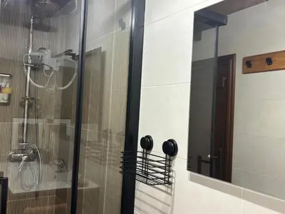 a shower with a glass door and a mirror at Albergue Rectoral de Romean in Lugo