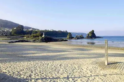 a beach with a wooden post in the sand at Destino Deluxe Mariña in Viveiro