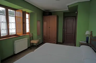 a bedroom with green walls and a bed and a chair at La Rectoral de San Juan in El Franco