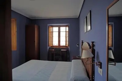a blue bedroom with a bed and a window at La Rectoral de San Juan in El Franco