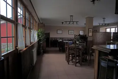 a dining room with tables and chairs and windows at La Rectoral de San Juan in El Franco