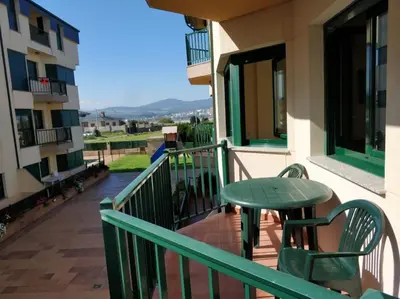 a green table and chairs on the balcony of a building at Apartamento Playa Catedrales in Barreiros