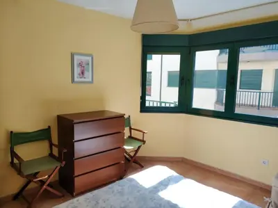 a bedroom with two chairs and a dresser and windows at Apartamento Playa Catedrales in Barreiros