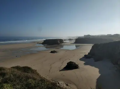 a beach with rocks and sand and the ocean at Apartamento Playa Catedrales in Barreiros