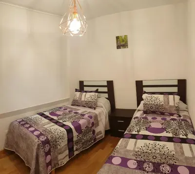 two beds in a room with purple comforters at Slow House Sarria in Sarria