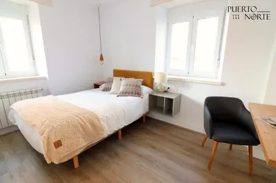 a bedroom with a bed and a desk and a chair at Apartamentos Puerto Norte - Apto 2 in Puerto de Vega