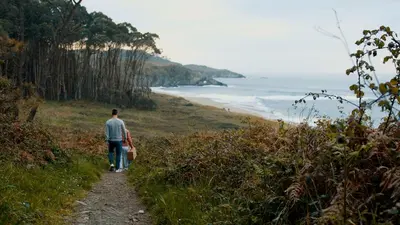 a man and a woman walking down a path near the ocean at Apartamentos Puerto Norte - Apto 2 in Puerto de Vega