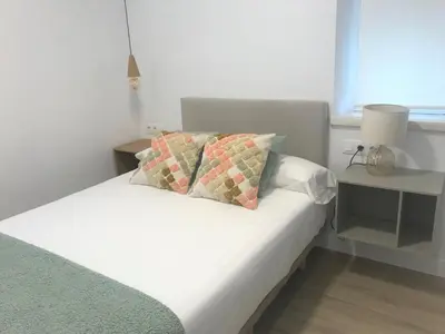 a bedroom with a white bed with a lamp and a table at Apartamentos Puerto Norte - Apto 3 in Puerto de Vega