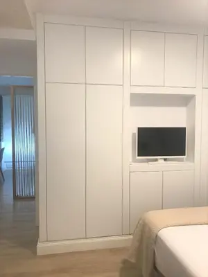 a white bedroom with a tv on a white cabinet at Apartamentos Puerto Norte - Apto 3 in Puerto de Vega