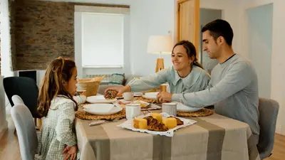 a family sitting at a table eating food at Apartamentos Puerto Norte - Apto 3 in Puerto de Vega