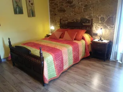 a bedroom with a bed with a colorful comforter at Casa Rural A Eira Vella in Padrón