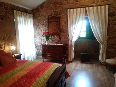 a bedroom with a bed and a stone wall at Casa Rural A Eira Vella in Padrón