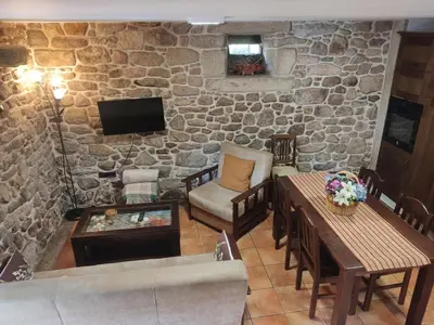 a living room with a stone wall at Casa Rural A Eira Vella in Padrón
