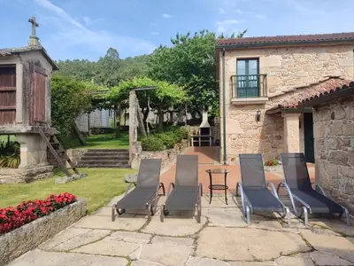 a patio with chairs and a table in a yard at Casa Rural A Eira Vella in Padrón