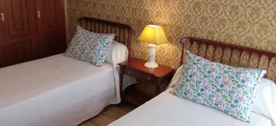 a bedroom with two beds and a lamp on a night stand at Casa independiente para grandes grupos y familias in Valeije