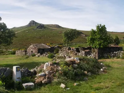 an old stone building in a field with a mountain in the background at Pension Casa Manolo in Fonsagrada