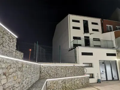 a white building at night with a stone wall at Los Tres Abetos in Arzúa