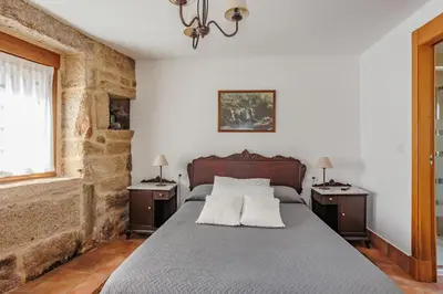a bedroom with a large bed with two night stands at Alojamiento Pazos in Cea