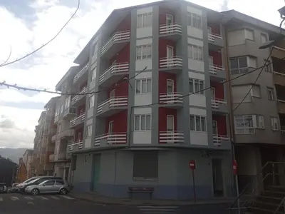 a tall apartment building with red and white balconies at Hostal Outarelo in Ourense
