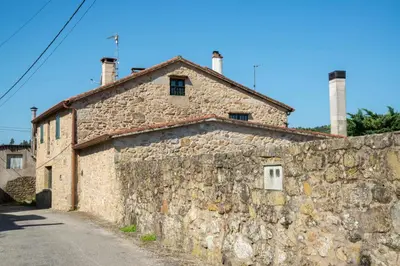 an old stone building next to a stone wall at CASA BELAI in Cuntis