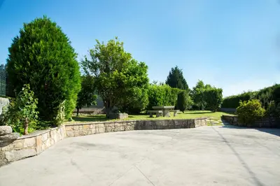 a park with a stone wall and a bench and trees at CASA BELAI in Cuntis