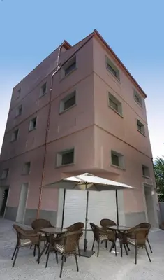 a building with tables and an umbrella in front of it at PENSIÓN BERENGUELA in Melide