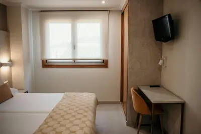 a bedroom with a bed and a window and a desk at PENSIÓN BERENGUELA in Melide