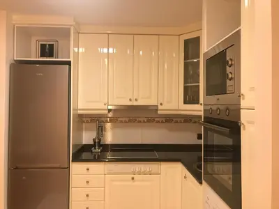 a kitchen with white cabinets and a stainless steel refrigerator at LUXURY DescansoTERMAL in Ourense