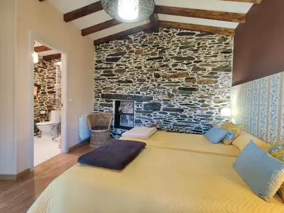 a bed in a room with a stone wall at Casa do Estevo in Francos