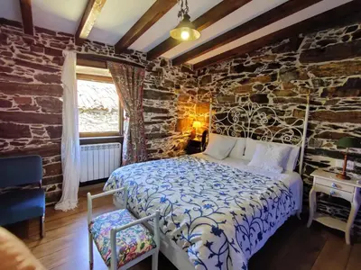 a bedroom with a bed and a stone wall at Casa do Estevo in Francos