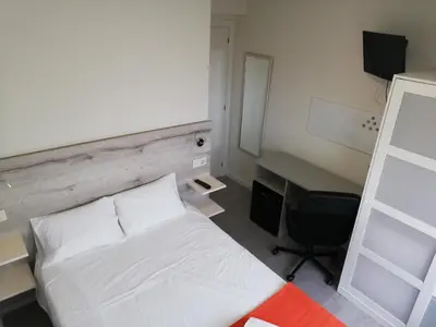 a bedroom with a white bed and a desk at Pensión La Intermodal in Santiago de Compostela
