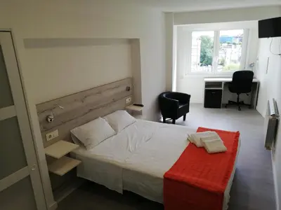 a bedroom with a bed with a red bench and a desk at Pensión La Intermodal in Santiago de Compostela