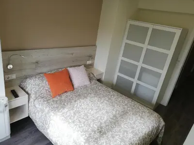 a bedroom with a bed with an orange pillow at Pensión La Intermodal in Santiago de Compostela